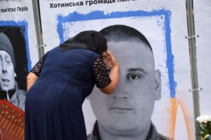 Une femme bouleversée s’appuie contre un mur affichant la photo d’un soldat ukrainien tombé au combat.